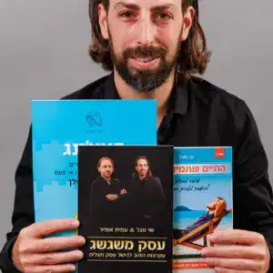 תמונה של שי מחזיק שלושה ספרים, כולל "עסק משגשג".